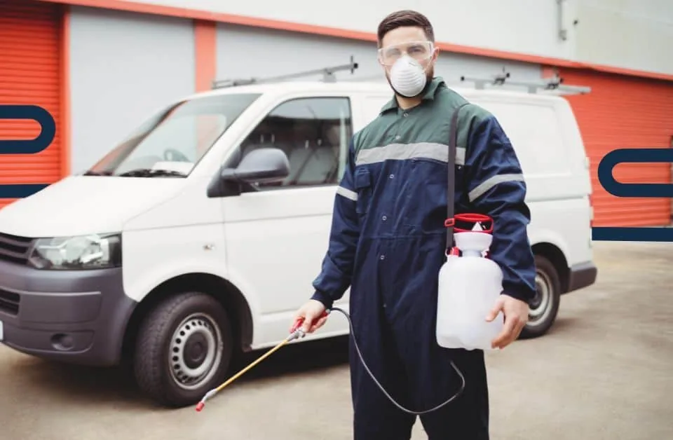 Pest control technician with a wand beside a service van